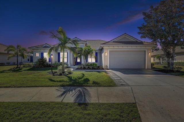 view of front of home featuring a yard, driveway, an attached garage, and stucco siding