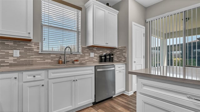 kitchen with tasteful backsplash, stainless steel dishwasher, wood finished floors, white cabinets, and a sink