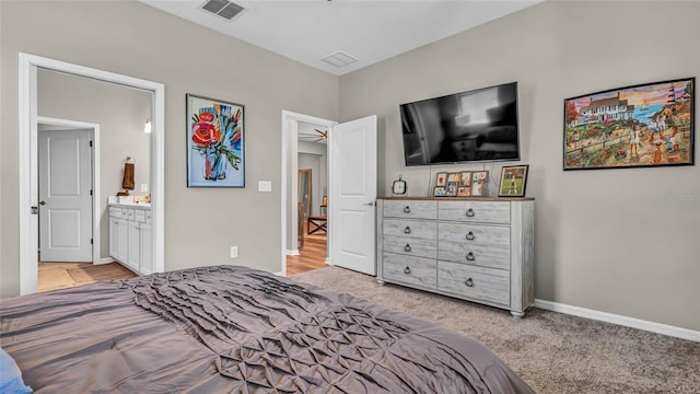 bedroom featuring visible vents, light colored carpet, connected bathroom, and baseboards