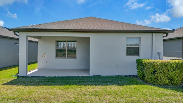 back of property featuring stucco siding, a patio, a lawn, and roof with shingles