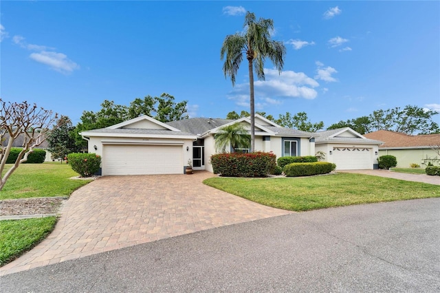 ranch-style house with stucco siding, decorative driveway, an attached garage, and a front yard