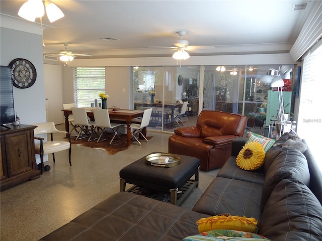 living area featuring visible vents, a healthy amount of sunlight, speckled floor, and a ceiling fan