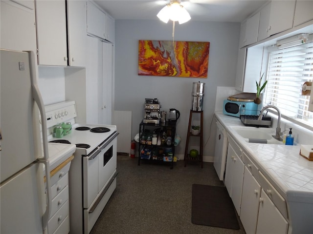 kitchen with white appliances, tile countertops, a ceiling fan, a sink, and white cabinets