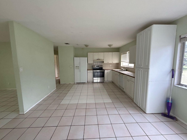 kitchen with a sink, under cabinet range hood, white appliances, white cabinets, and light tile patterned floors