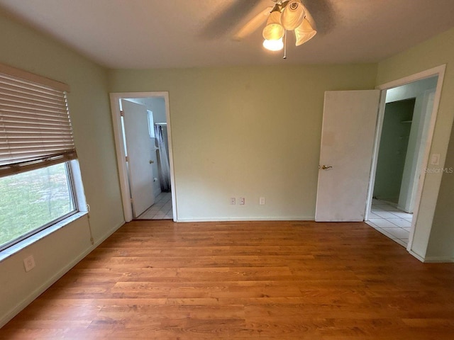 unfurnished bedroom with baseboards, ensuite bath, and light wood-style flooring