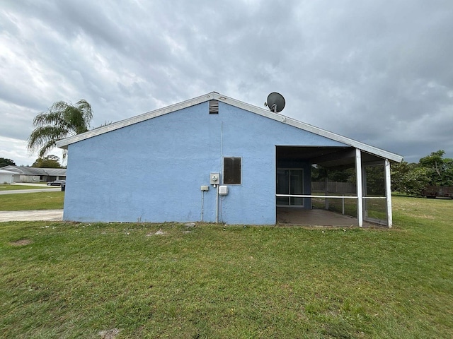 view of property exterior with stucco siding, a lawn, and a sunroom