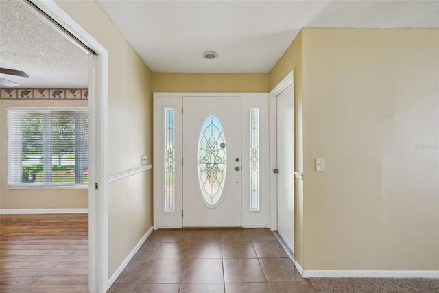 entrance foyer with tile patterned floors, a ceiling fan, baseboards, and a textured ceiling