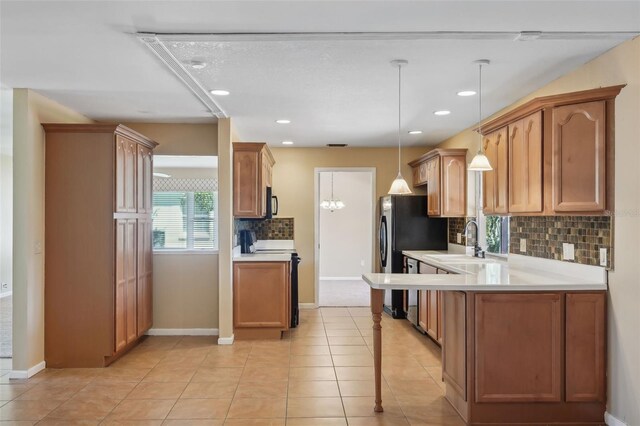 kitchen with electric range, a sink, backsplash, light countertops, and light tile patterned floors