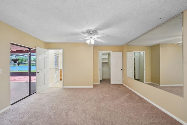 unfurnished room with a textured ceiling, baseboards, carpet, and ceiling fan