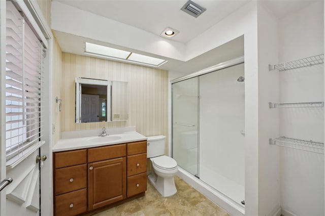 bathroom with vanity, visible vents, a skylight, a shower stall, and toilet