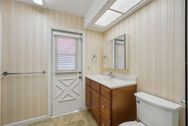 half bath with wallpapered walls, toilet, and vanity