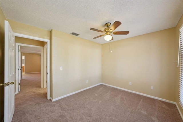 empty room with visible vents, carpet, a ceiling fan, and a textured ceiling