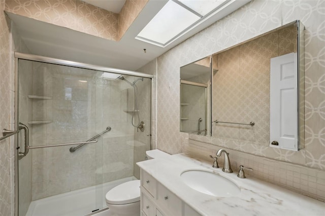 bathroom featuring toilet, a stall shower, wallpapered walls, and vanity