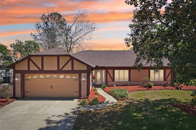 tudor house featuring brick siding, an attached garage, concrete driveway, and roof with shingles