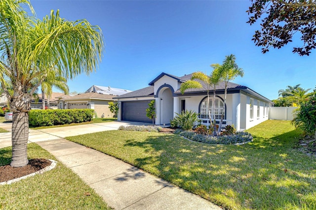 view of front facade with an attached garage, fence, a front yard, stucco siding, and driveway