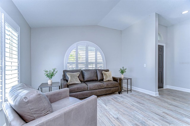 living area with lofted ceiling, baseboards, and light wood finished floors