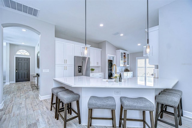 kitchen featuring visible vents, glass insert cabinets, high quality fridge, arched walkways, and white cabinets