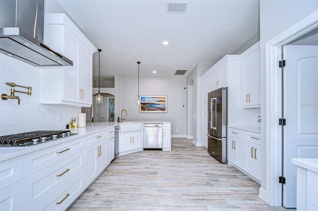 kitchen featuring visible vents, a sink, light countertops, appliances with stainless steel finishes, and wall chimney range hood