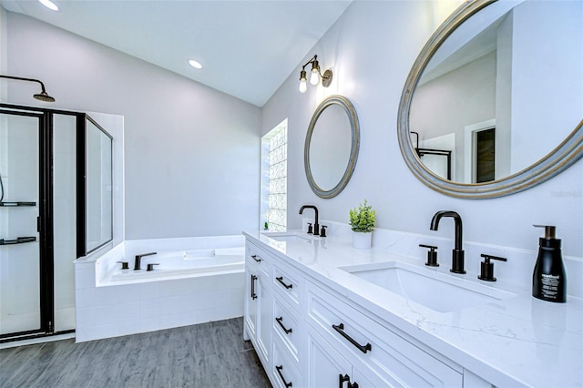 full bathroom with a sink, wood finished floors, a bath, and vaulted ceiling