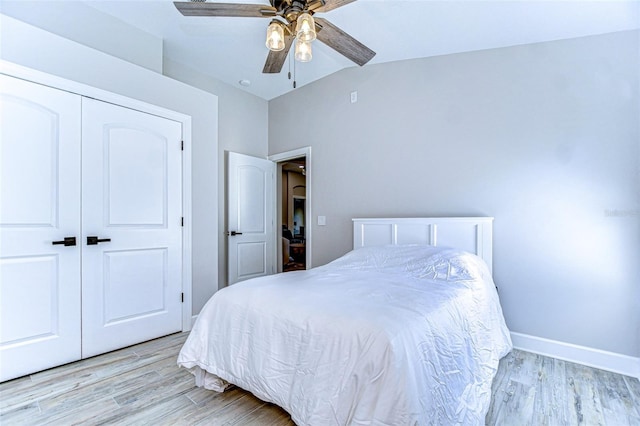 bedroom featuring vaulted ceiling, baseboards, light wood-type flooring, and a closet