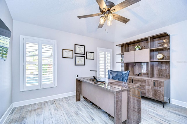 home office with baseboards, ceiling fan, and light wood finished floors