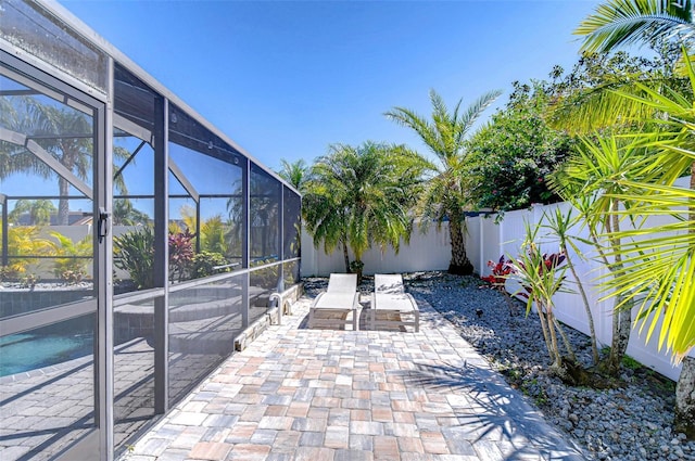 view of patio featuring glass enclosure and a fenced backyard