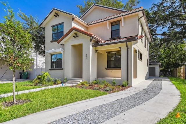 mediterranean / spanish-style home with a tile roof, a garage, a front yard, and stucco siding