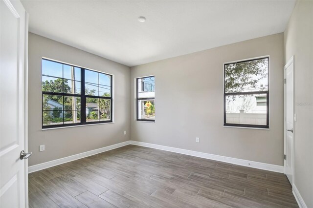 spare room with baseboards and wood finished floors