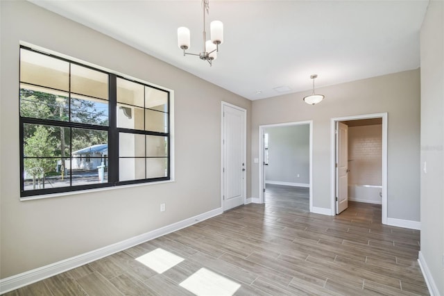 unfurnished room featuring baseboards, a notable chandelier, and wood tiled floor