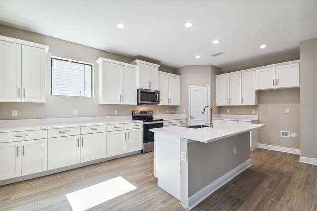 kitchen featuring a sink, wood finish floors, white cabinets, and stainless steel appliances