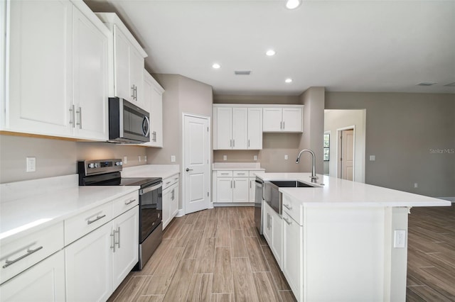 kitchen featuring a sink, recessed lighting, appliances with stainless steel finishes, white cabinets, and wood tiled floor