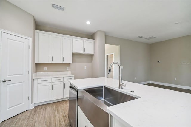 kitchen with visible vents, light wood finished floors, a sink, white cabinets, and dishwasher