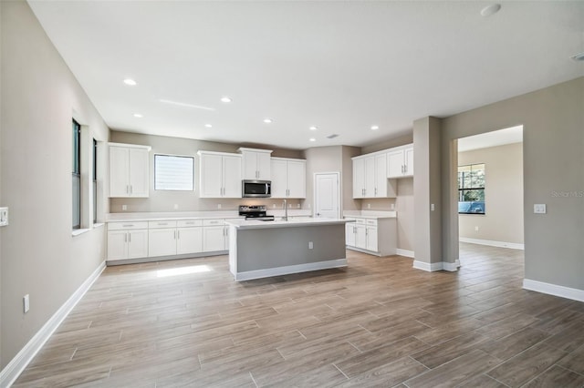 kitchen featuring baseboards, light wood-style flooring, light countertops, white cabinets, and appliances with stainless steel finishes