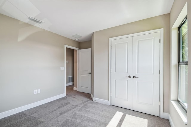 unfurnished bedroom featuring light carpet, visible vents, a closet, and baseboards