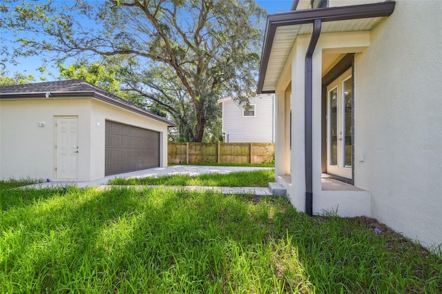 view of yard featuring fence, a garage, and french doors