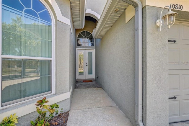 entrance to property with a garage and stucco siding