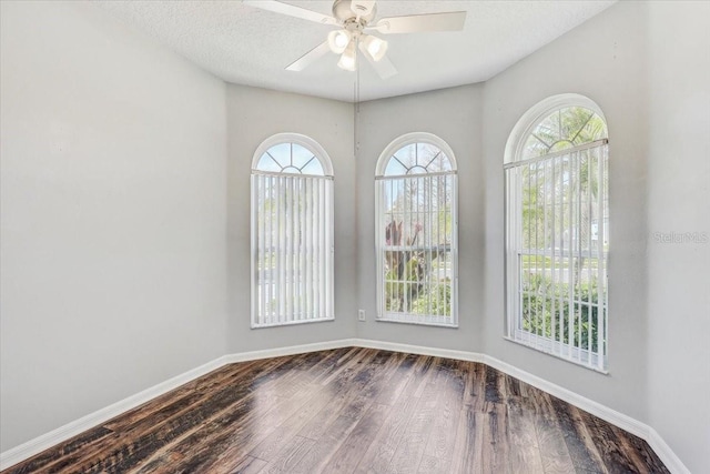 spare room with a textured ceiling, wood finished floors, baseboards, and ceiling fan