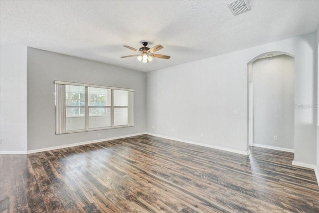 unfurnished room featuring a ceiling fan, wood finished floors, visible vents, baseboards, and arched walkways