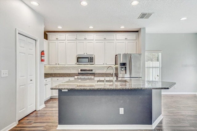 kitchen with visible vents, stainless steel appliances, wood finished floors, and a sink