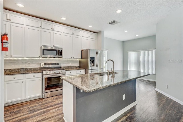 kitchen with visible vents, a sink, backsplash, dark wood-style floors, and appliances with stainless steel finishes