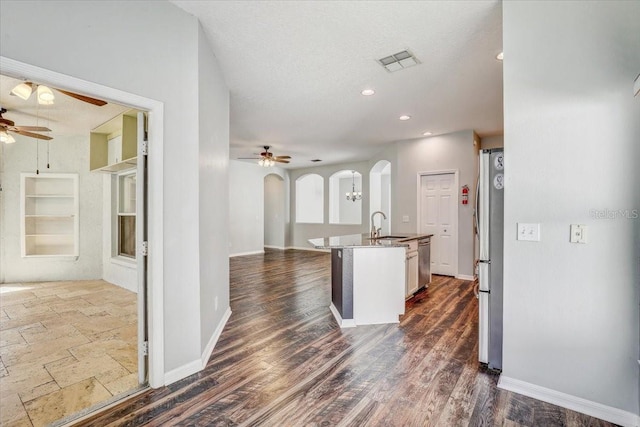 kitchen with stainless steel appliances, arched walkways, ceiling fan, and open floor plan