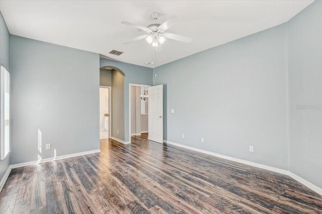 unfurnished bedroom featuring arched walkways, visible vents, baseboards, and wood finished floors