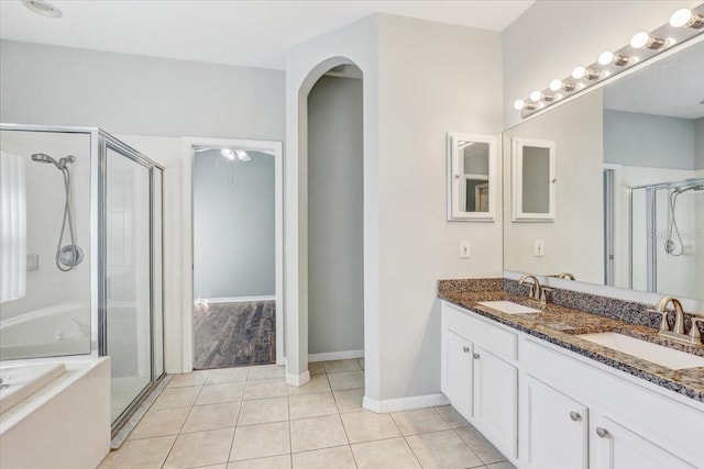 bathroom with tile patterned floors, a shower stall, a garden tub, and a sink