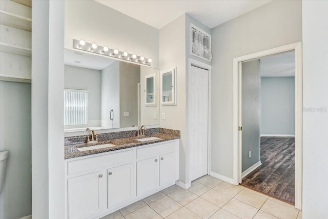 full bathroom featuring tile patterned floors, double vanity, baseboards, and a sink