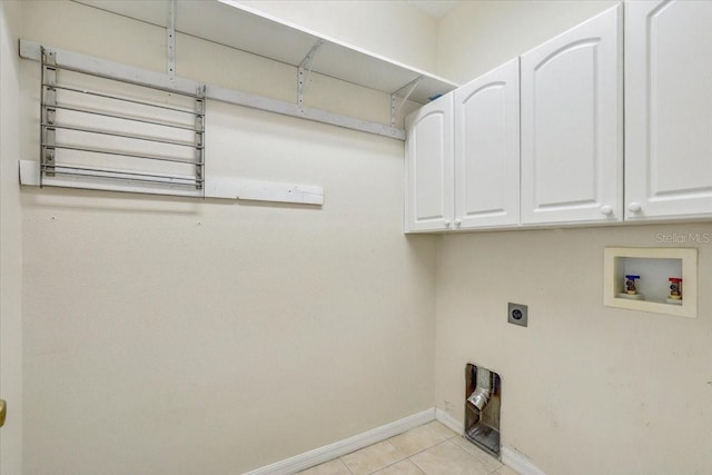 clothes washing area with electric dryer hookup, cabinet space, light tile patterned flooring, baseboards, and hookup for a washing machine