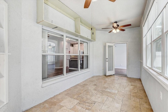 unfurnished sunroom featuring ceiling fan