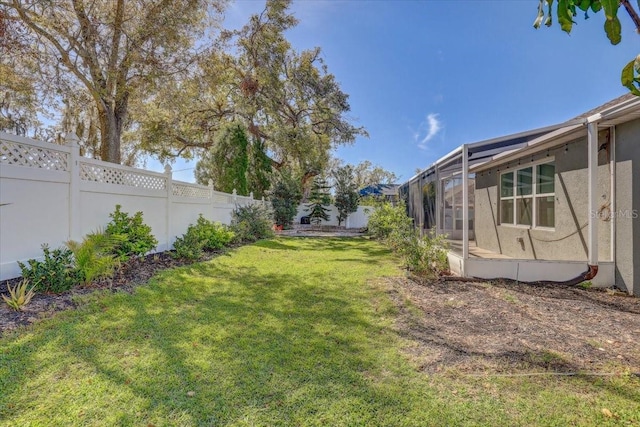 view of yard featuring glass enclosure and a fenced backyard