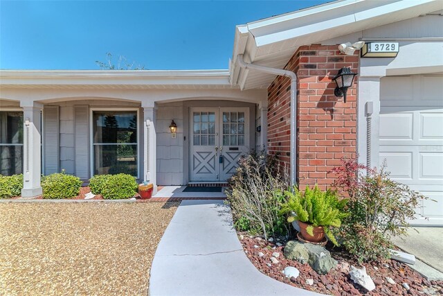 doorway to property with an attached garage and brick siding