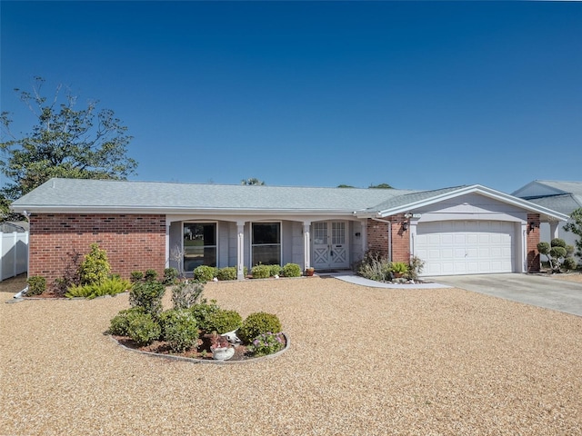 single story home featuring brick siding, concrete driveway, a garage, and fence