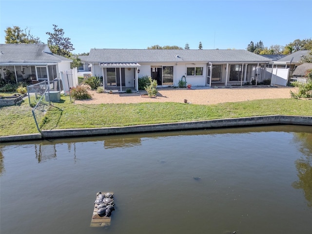 rear view of property featuring a yard, a water view, and a sunroom